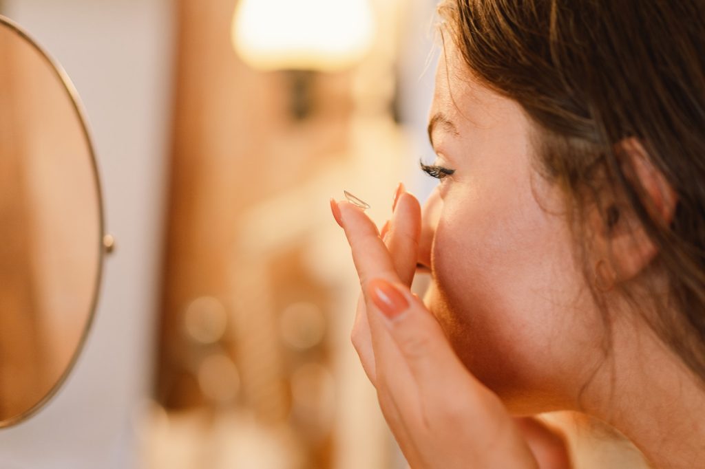 Contact Lens For Vision Concept. Portrait of girl applying eye lens in the bathroom