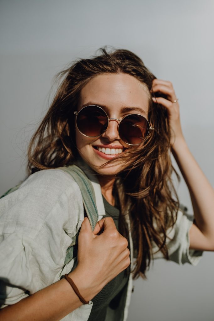 Portrait of happy young woman outdoor with backpack and sunglasses.