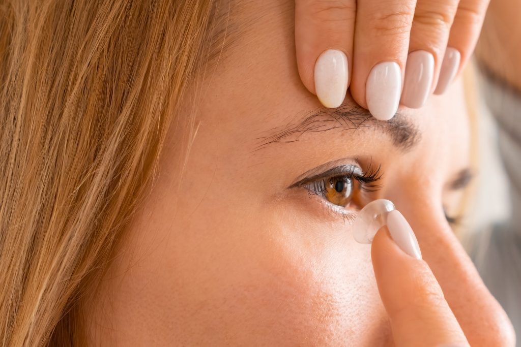 Smiling woman applying contact eye lenses